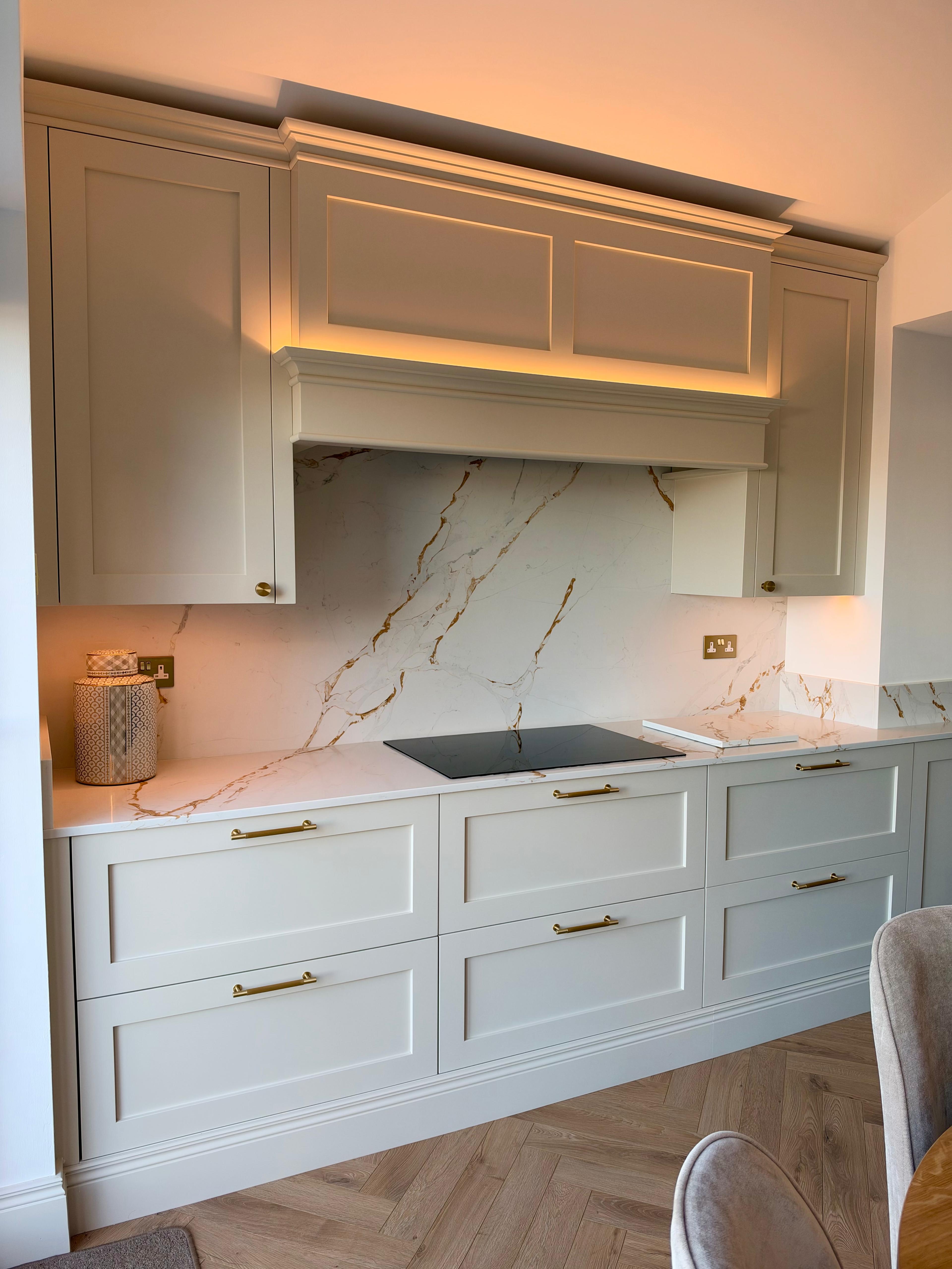 Bespoke kitchen cabinetry with warm lighting and marble splashback