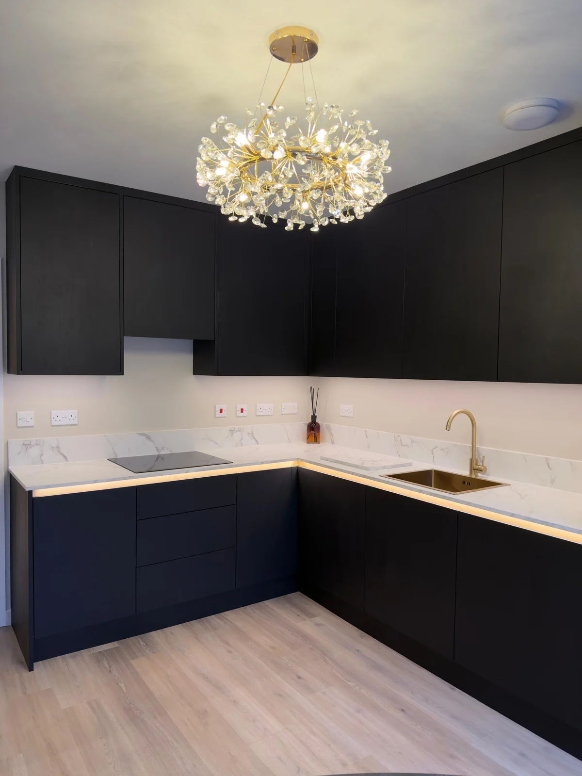 Dark bespoke kitchen with marble worktops and brass fittings